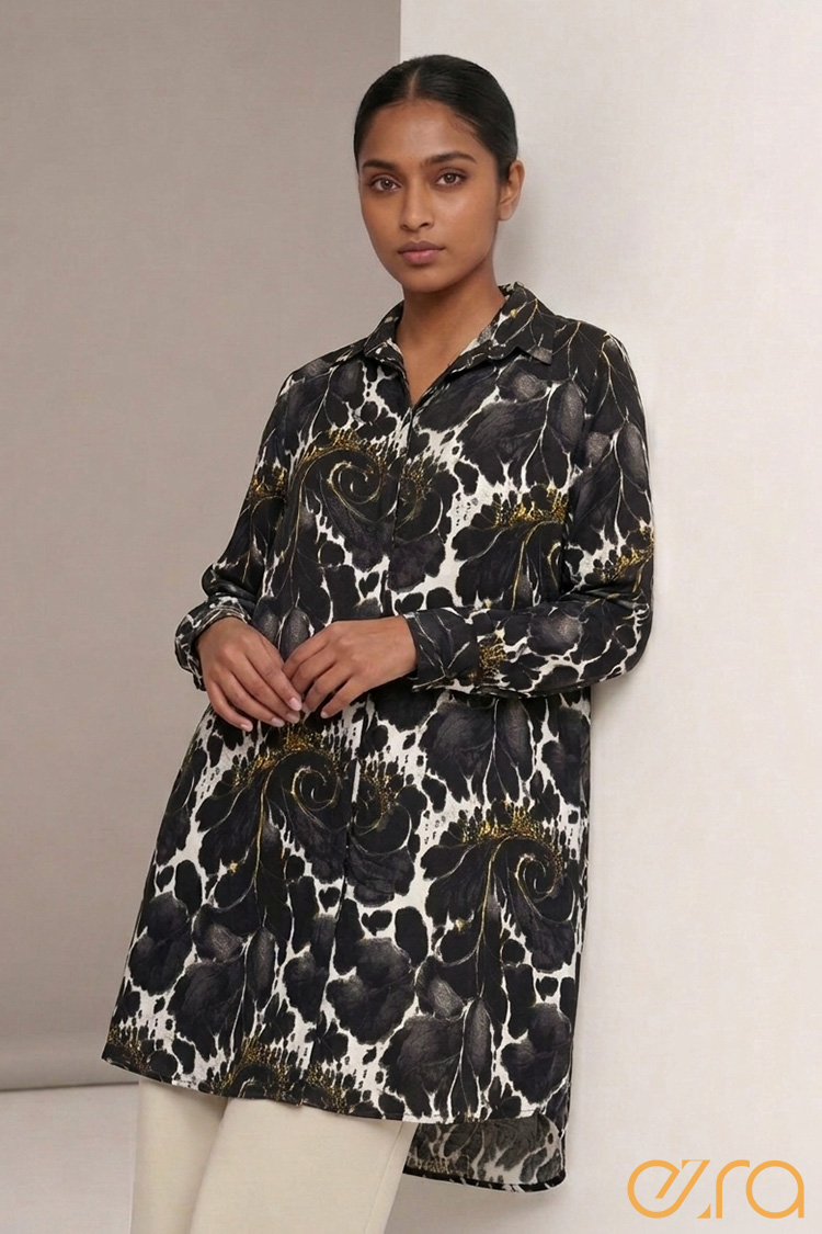 A woman posing in a long sleeve Ezra tunic shirt featuring a black, white, and gold baroque floral print